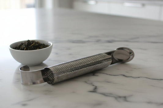 Metallic loose-leaf tea infuser on a marble countertop